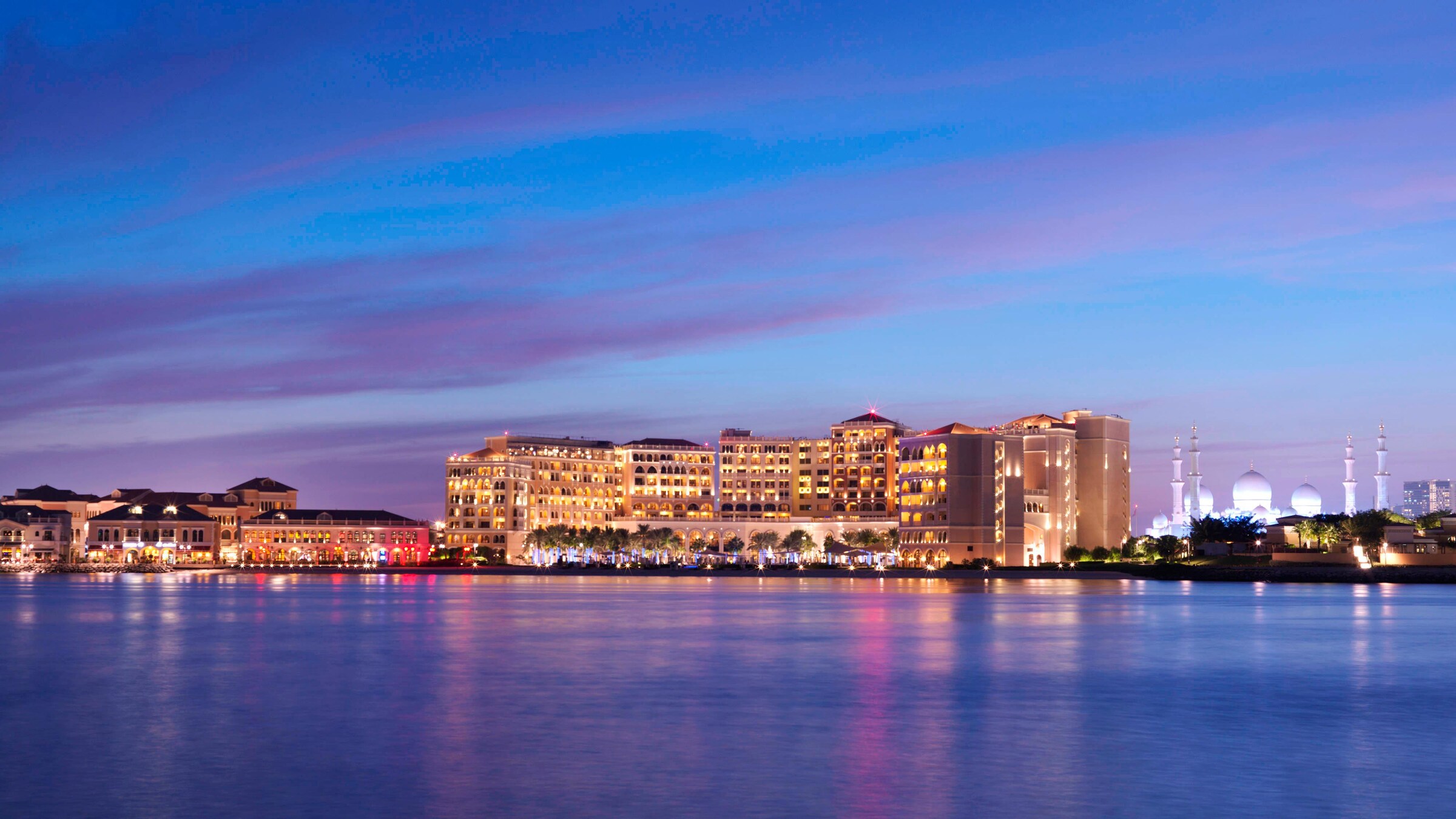 The Ritz-Carlton Abu Dhabi illuminated beside the Grand Canal at dusk